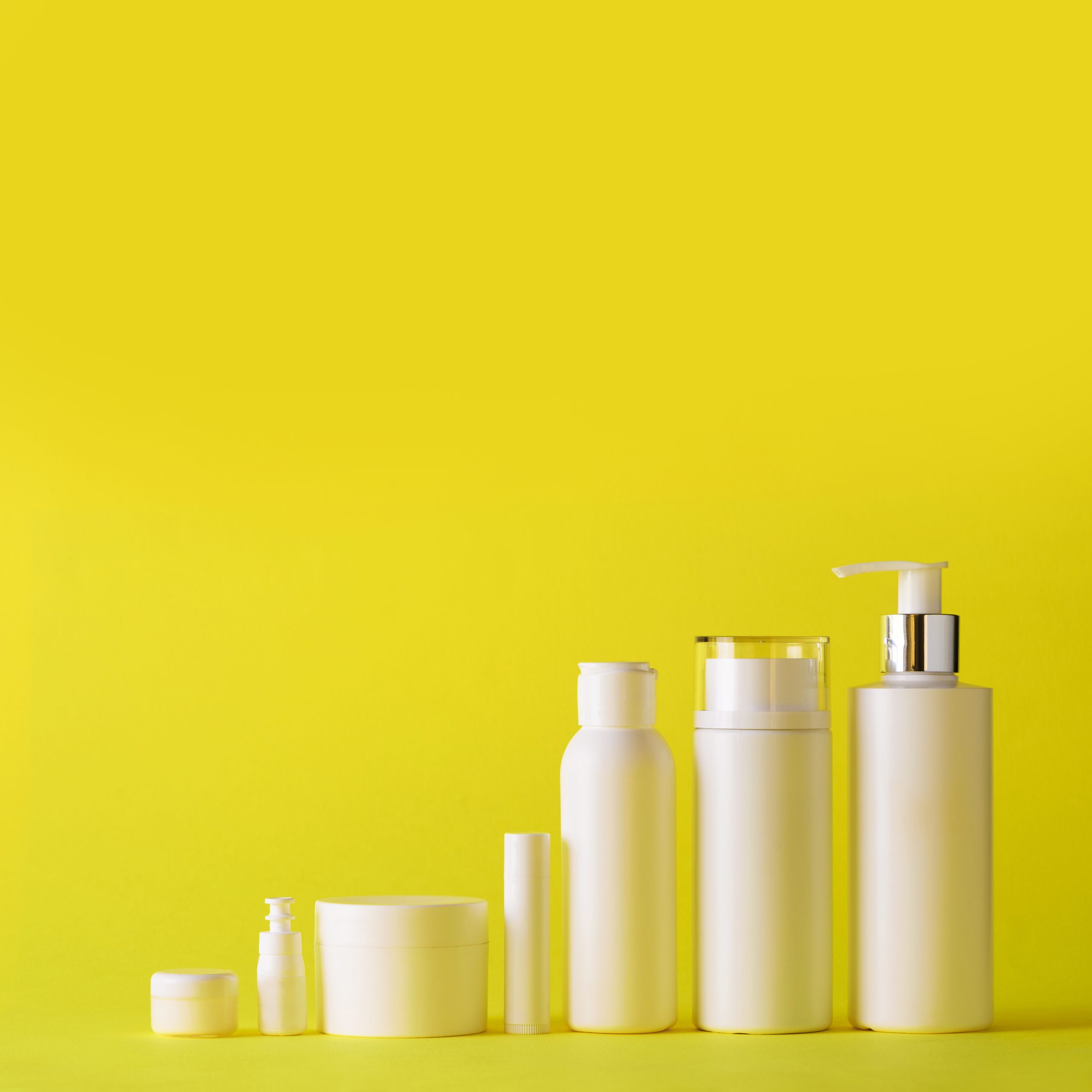 White cosmetic tubes on yellow background with copy space. Skin care, body treatment, beauty concept. Square crop